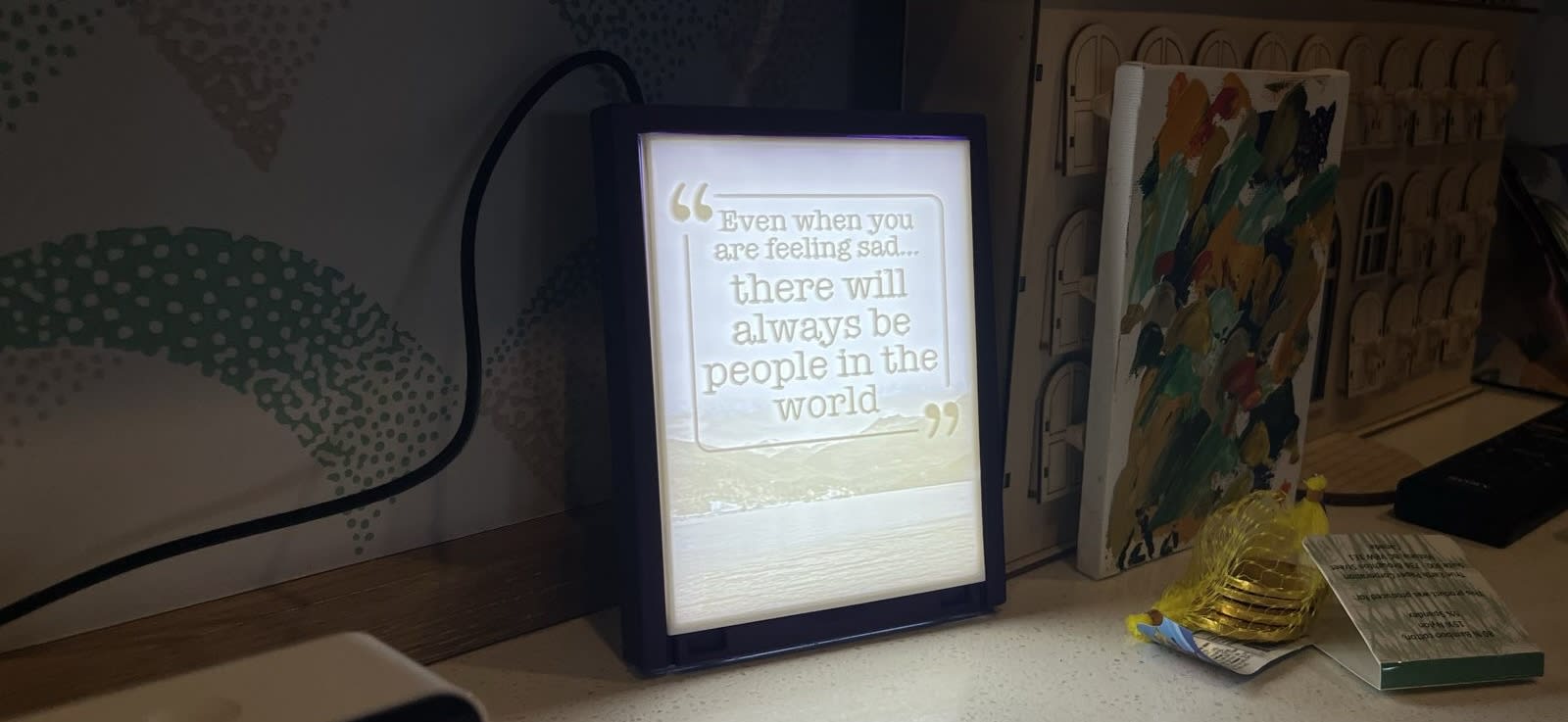 A rectangular box with a printed image that says even when you are feeling sad, there will always be people in the world