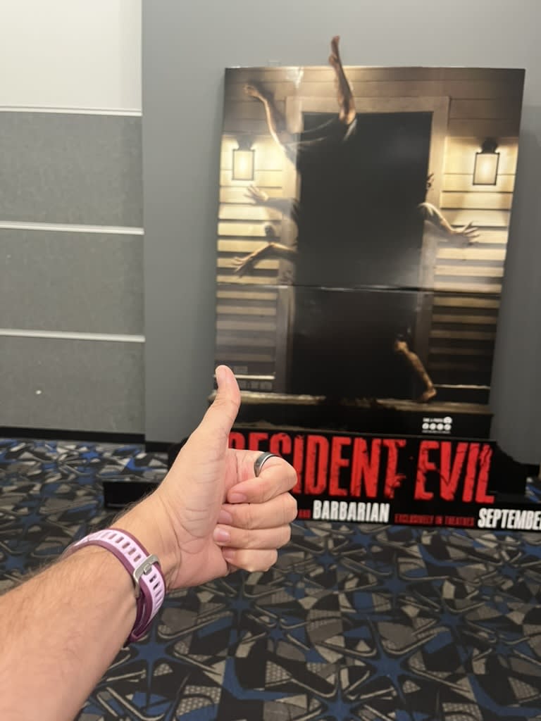 A photo of the Resident Evil poster which shows arms and legs coming out of a house and my arm in front of it giving the thumbs up