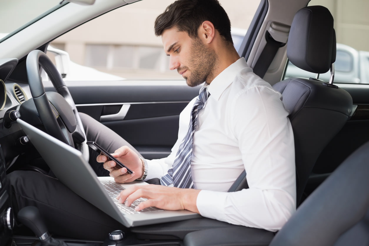 image of a person distracted from driving with computer and phone