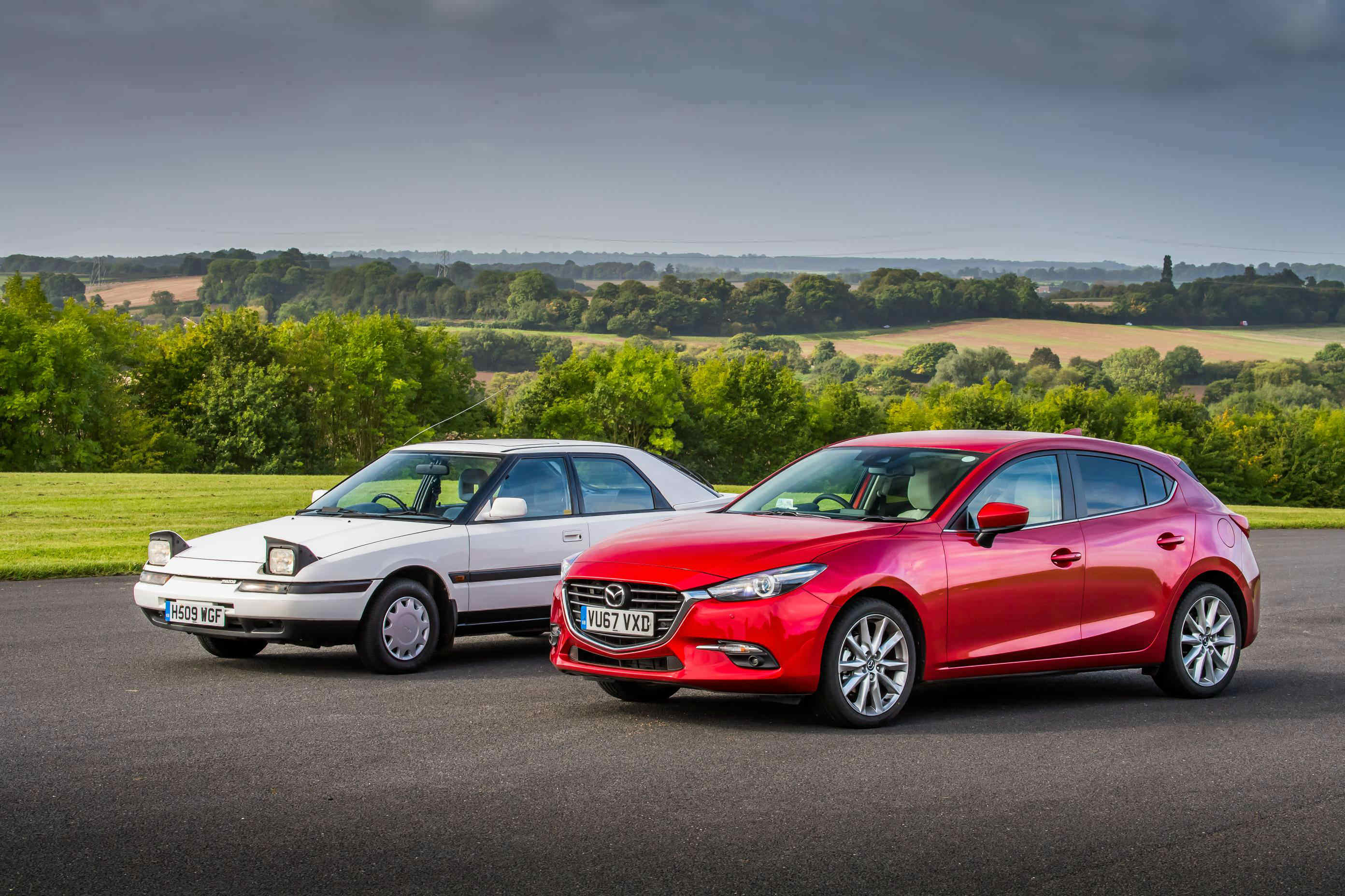 image of an old mazda car next to a new mazda car on the road