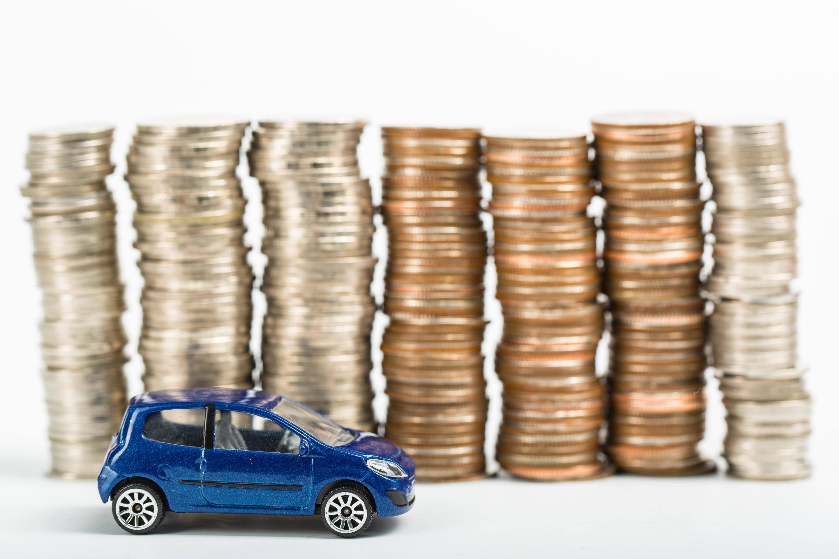 image of a model car next to a stacks of coins