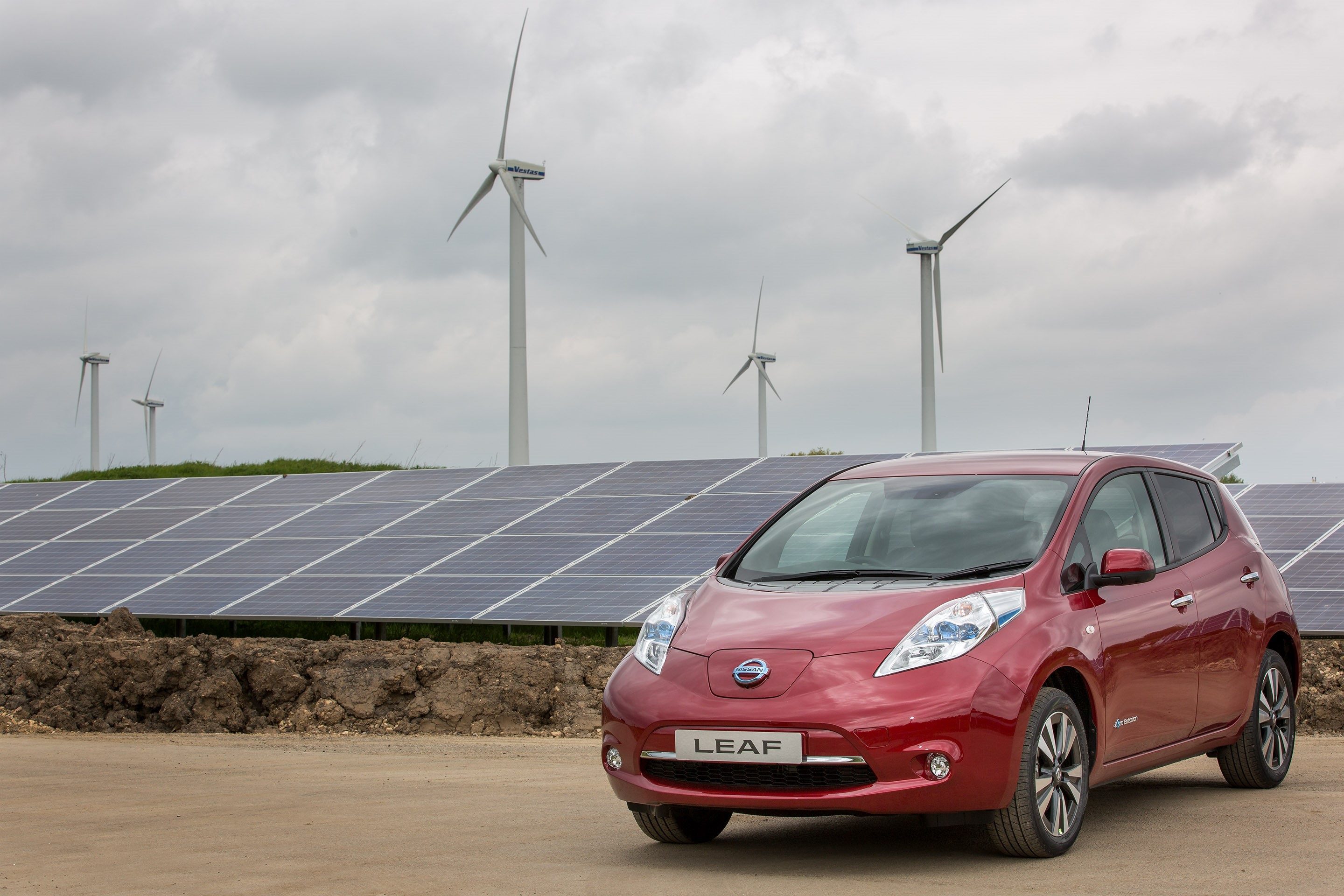 image of a red nissan leaf electric car parked next to solar panels