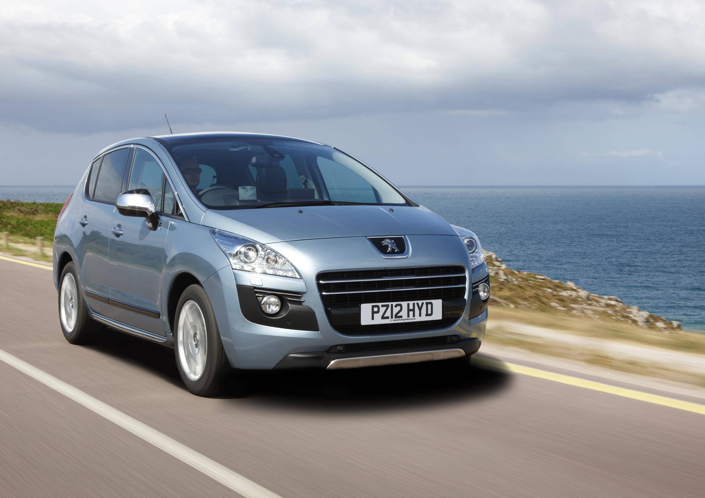 Man driving a Grey Hybrid SUVs Peugeot 3008 near the sea