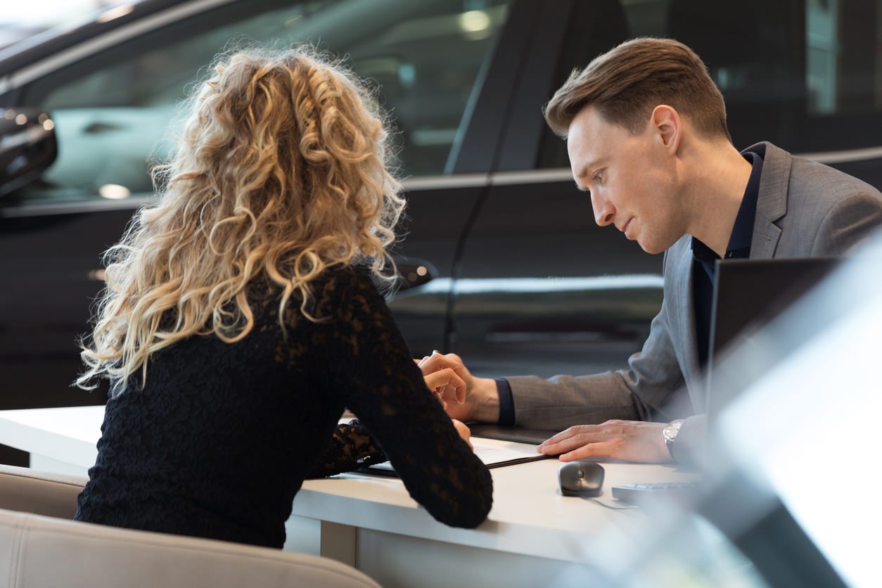 A woman and a man overlooking details on a document in a dealership