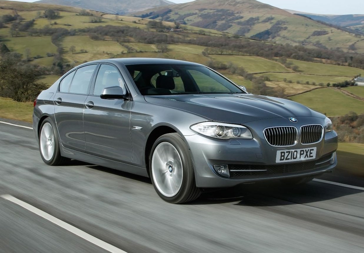 Grey BMW 5-Series driving through countryside 