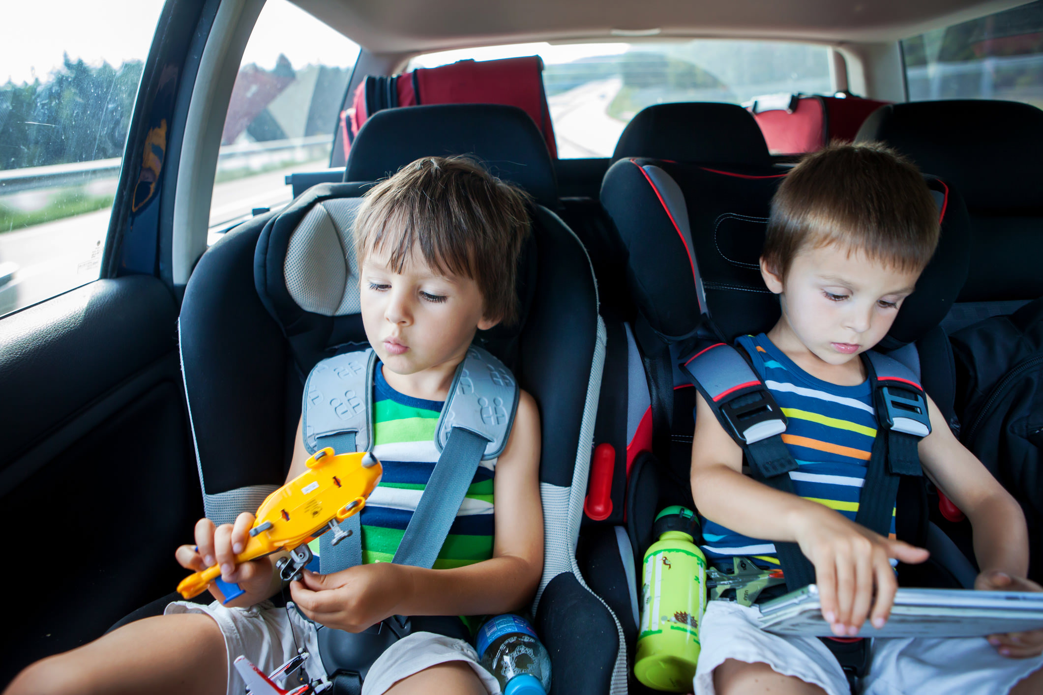 Two kids playing with toys. essential accessories to pack in a car for a road trip