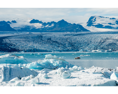 snowy mountains and coastline with a small boat near the shore