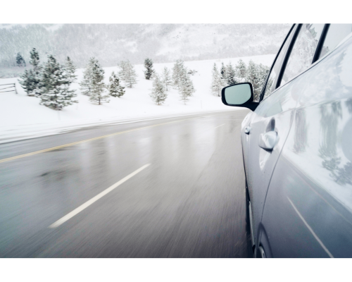 side of silver car driving on snowy road