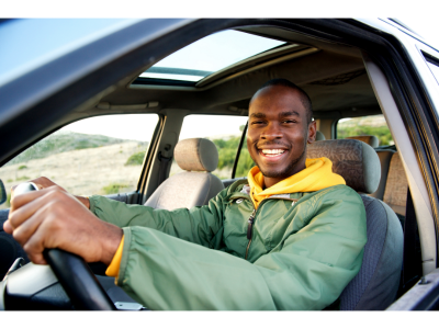 smiling young man sitting in the drivers seat of a car