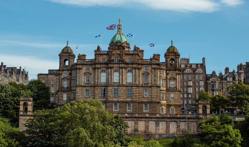 Bank of Scotland Headquarters building on the Mound in Edinburgh. The building has large windows and has a blue dome with flags on top.
