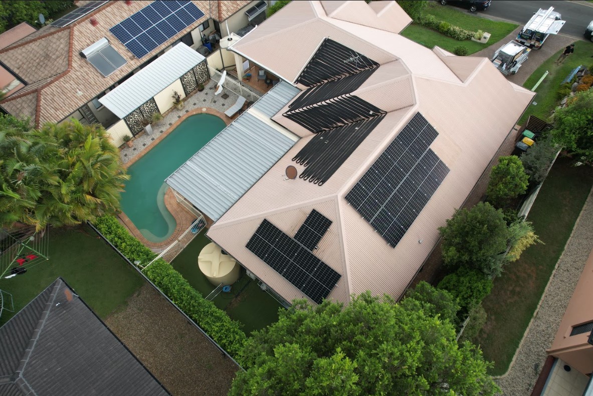 Aerial view of a Brisbane home with solar panels installed on the roof by Exclusive Electrical & Air, showcasing a modern energy solution alongside a backyard swimming pool.