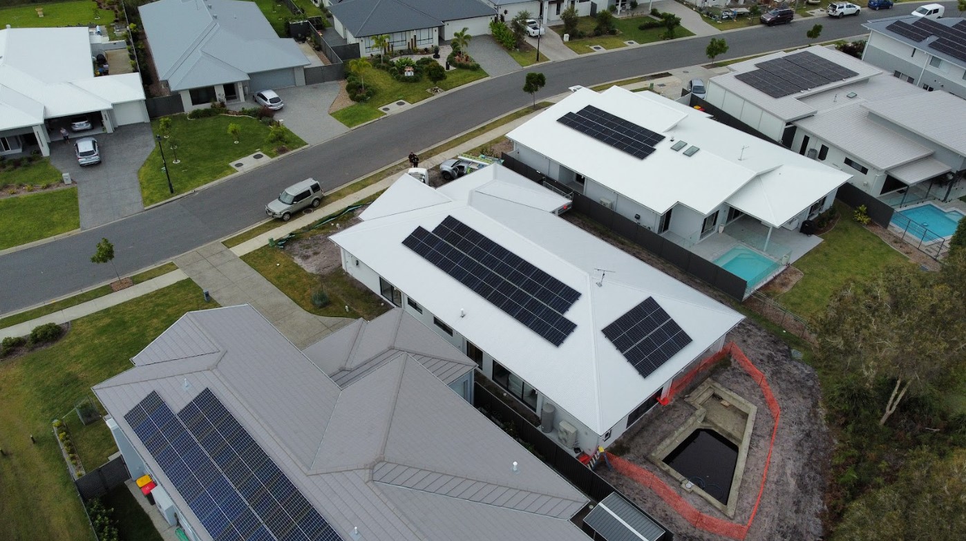 Aerial view of modern Brisbane homes featuring newly installed rooftop solar panels by Exclusive Electrical & Air, providing clean renewable energy and efficiency.