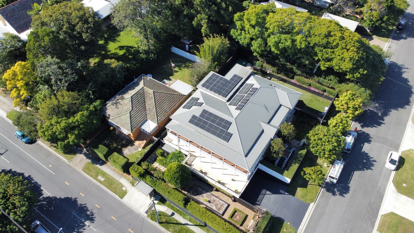 Aerial view of a large Brisbane home with multiple rooftop solar panel arrays installed by Exclusive Electrical & Air, maximizing energy efficiency and renewable power.