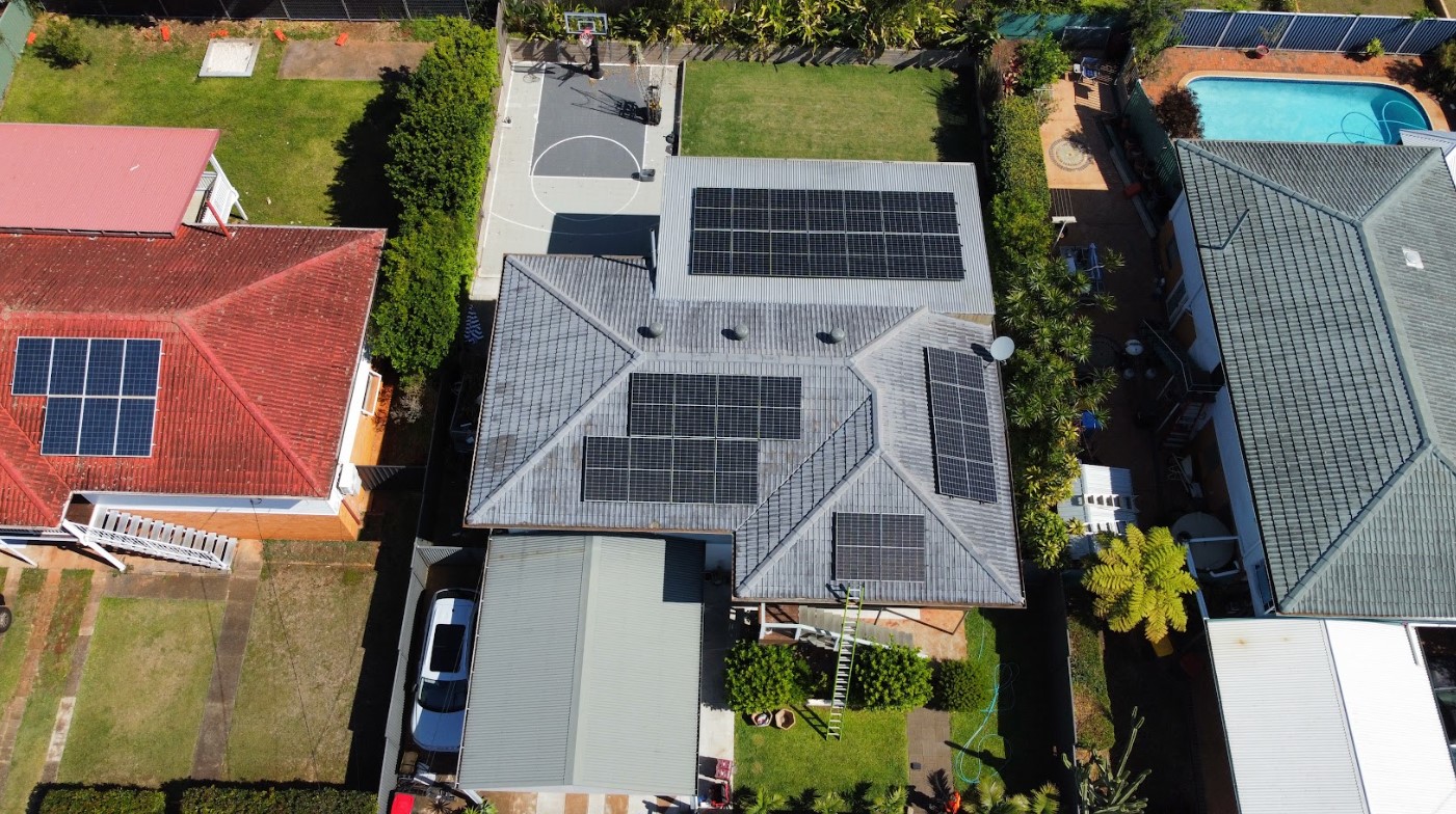 Aerial view of a modern home in Brisbane with multiple solar panel arrays installed across the roof, showcasing an efficient layout for maximum energy capture.
