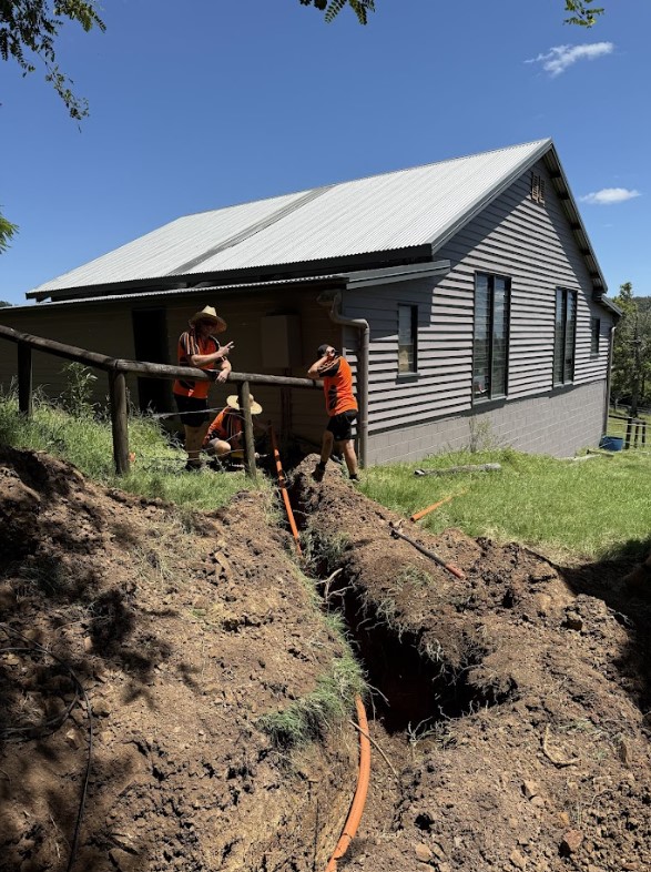 lectricians from Exclusive Electrical & Air working on underground trenching installation for power cables outside a residential property, ensuring safe and efficient electrical connections.