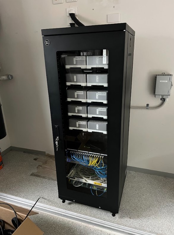 A modern black server cabinet neatly housing labeled network equipment and organized cabling, installed by Exclusive Electrical & Air for reliable connectivity and structured data management.