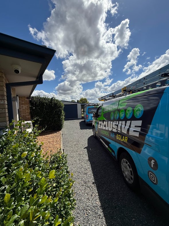 Exclusive Electrical & Air branded vans parked in a residential driveway under a bright blue sky, showcasing the company’s professional presence during an electrical service project.