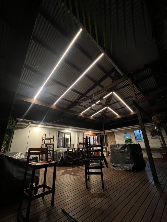 A covered outdoor patio with sleek LED strip lighting installed along the ceiling beams, creating a stylish and well-lit entertainment space.