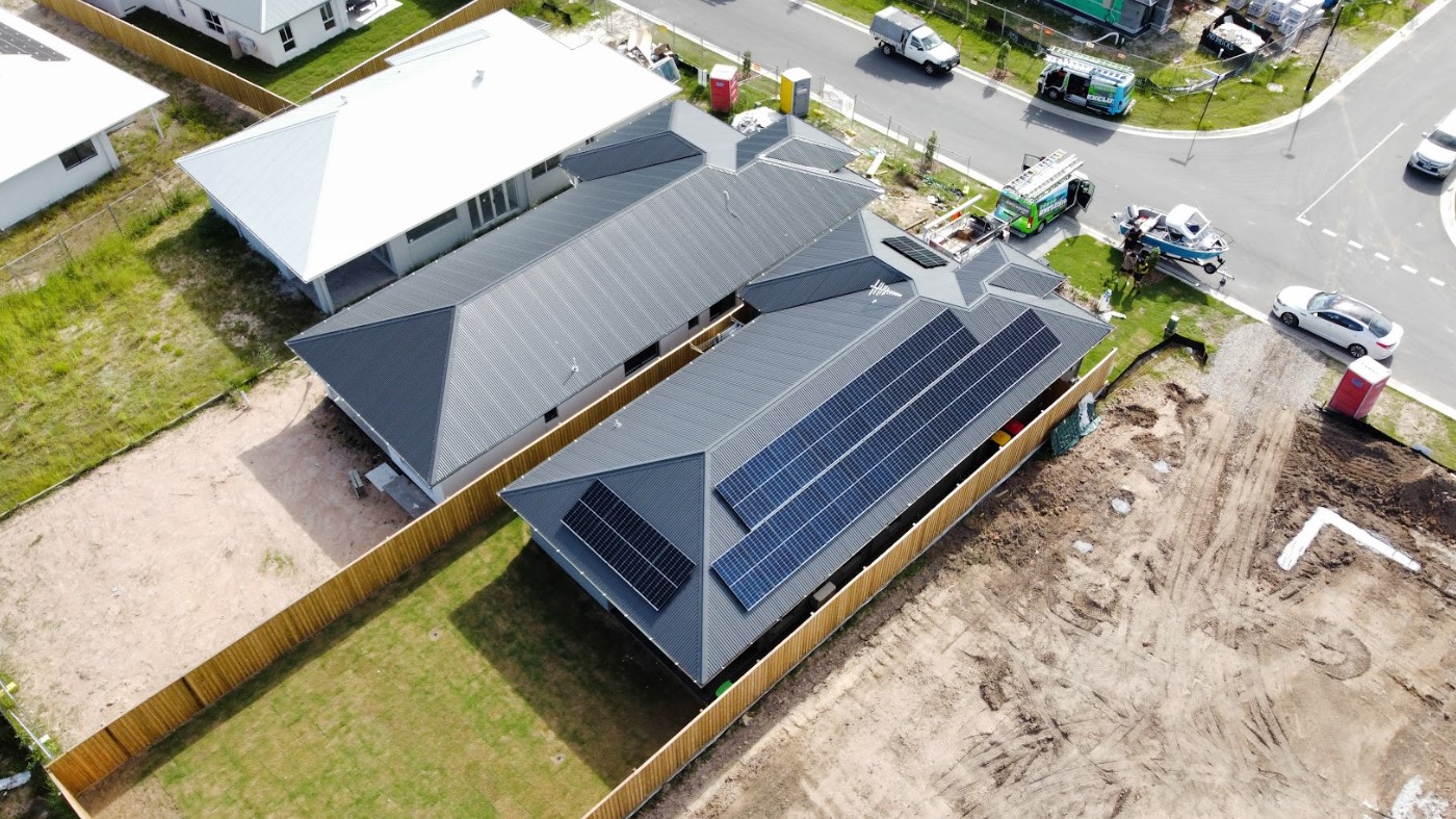 Aerial view of a residential solar panel installation on a modern home with a grey roof, completed by Exclusive Electrical & Air in Brisbane, showcasing a large array of rooftop solar panels for clean energy efficiency.