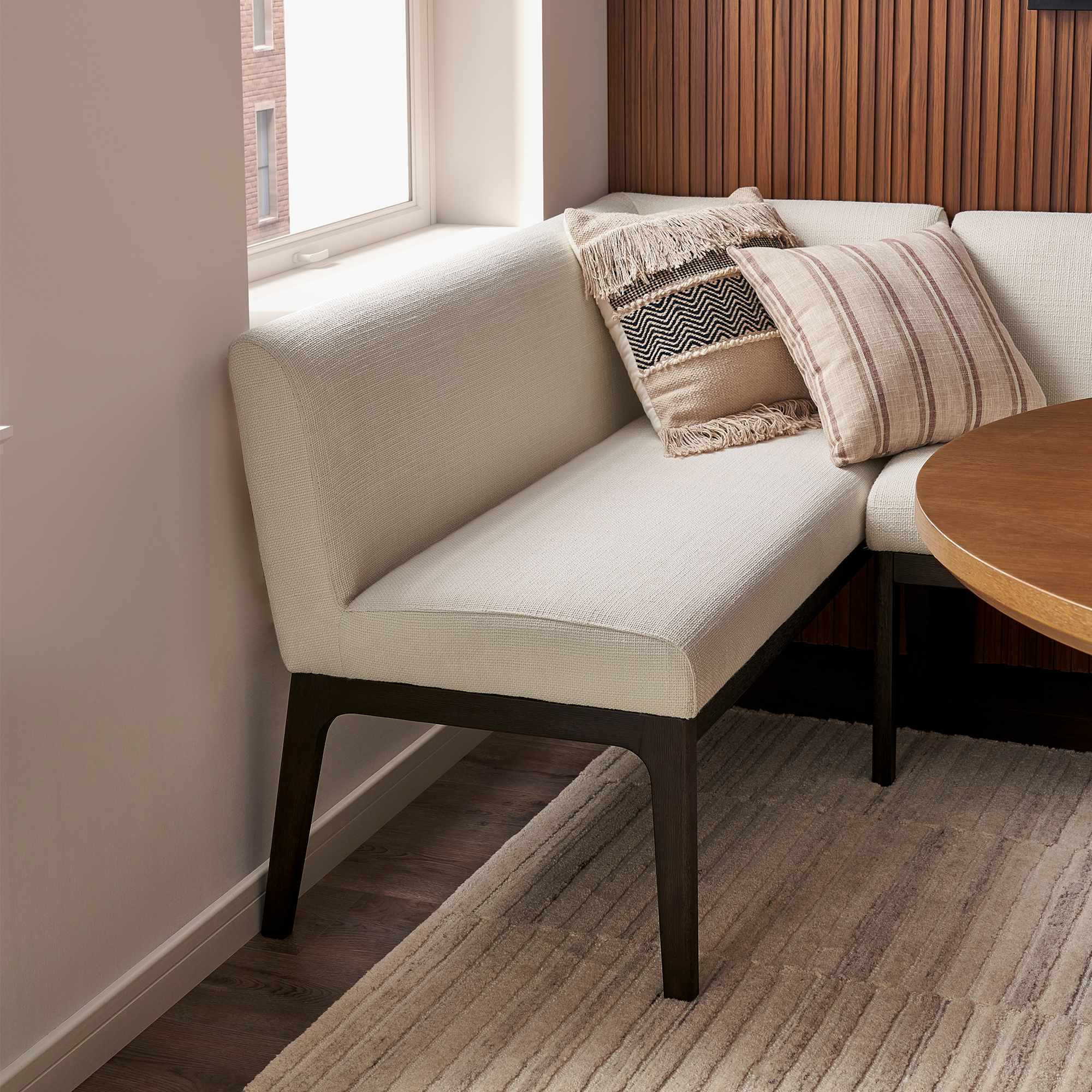 Close-up of a cream textured banquette bench with decorative pillows.
