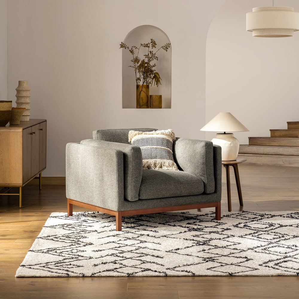 An armchair placed atop a rug with a geometric pattern.