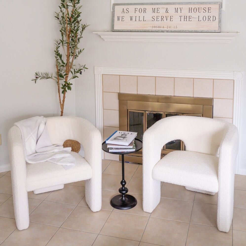 Two bouclé armchairs in front of a fireplace. 