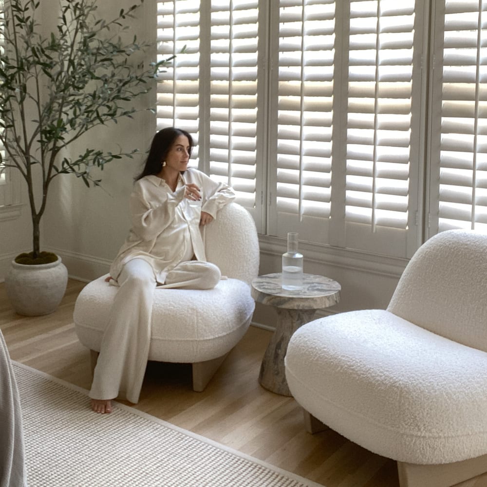 A person sitting on a sherpa chair placed near a window.