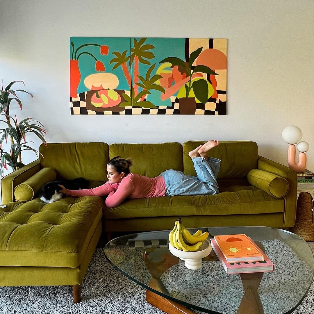 A person lounging on a yellow sofa with their cat.