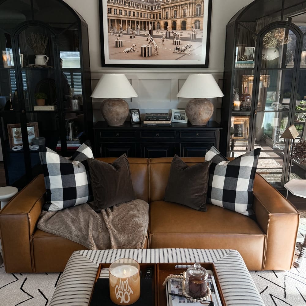 A leather sofa decorated with black checkered pillows and a throw.