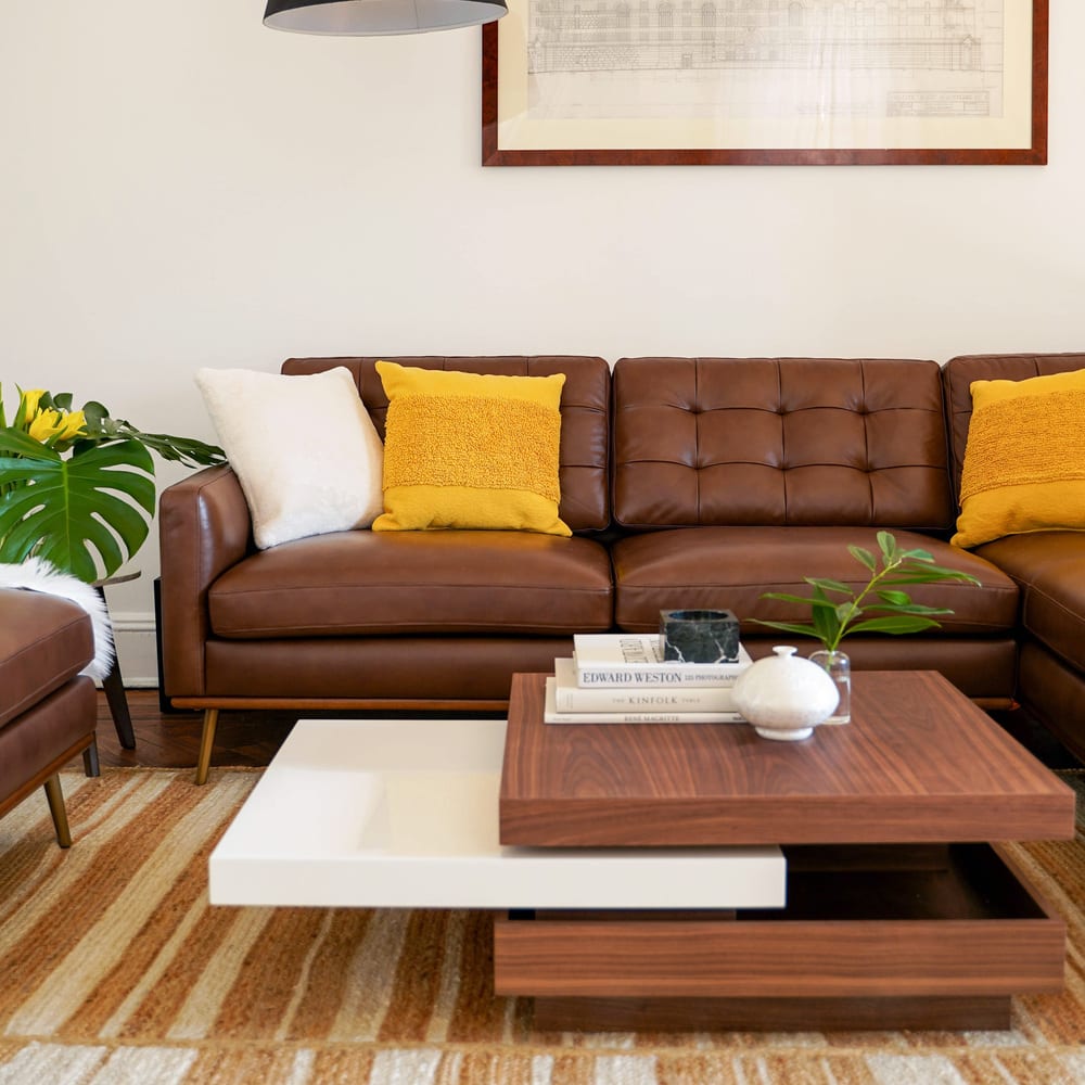 A leather sofa decorated with bright yellow and white cushions.