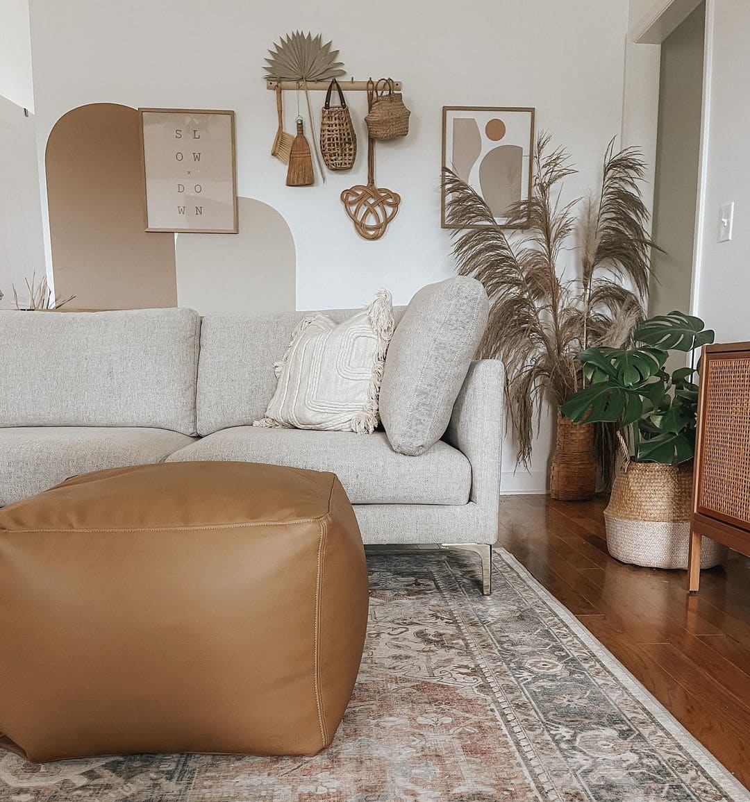 A living room with brown decor, a grry sofa, and a leather ottoman.