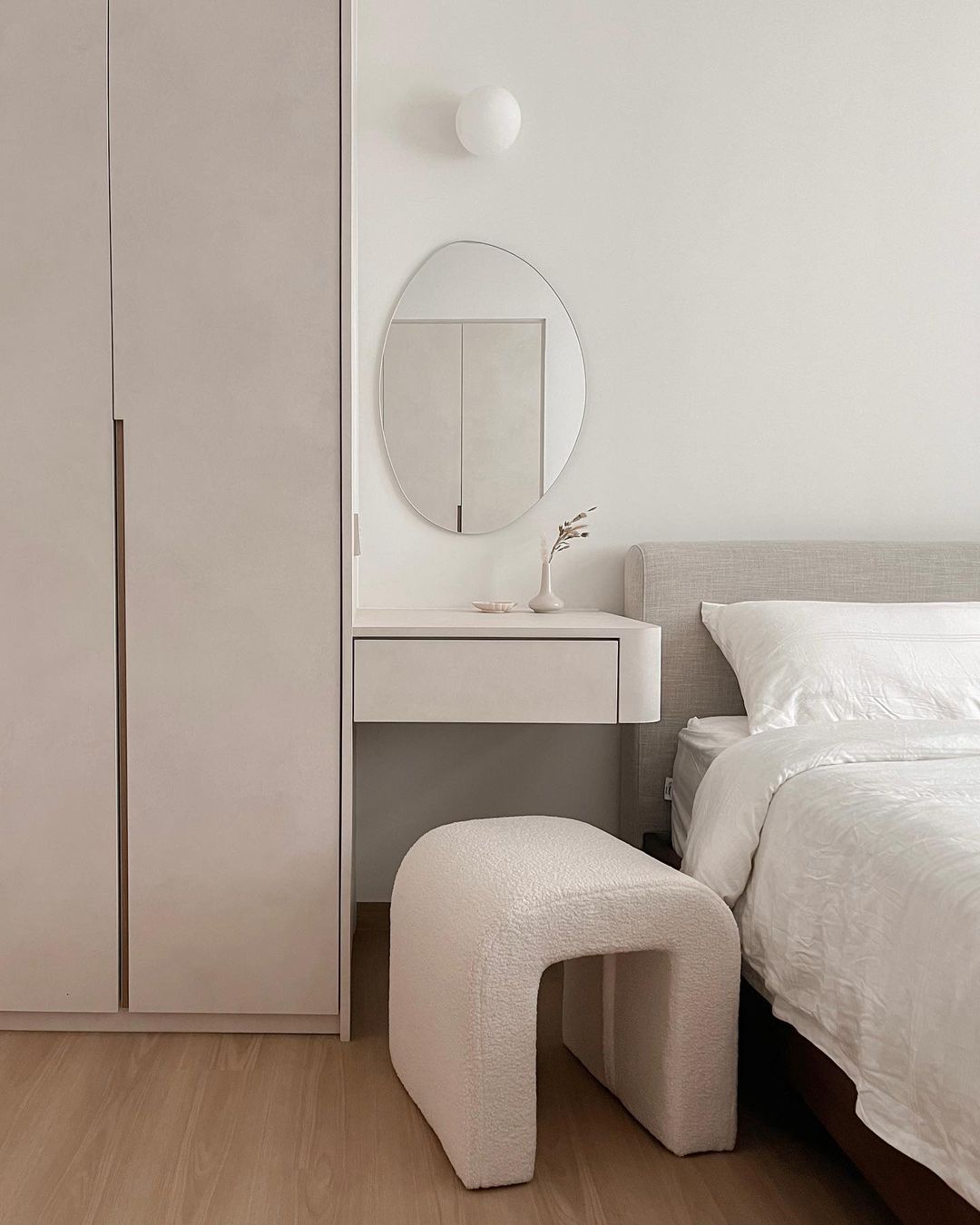 A gray bed frame beside a side table doubled up as a vanity.