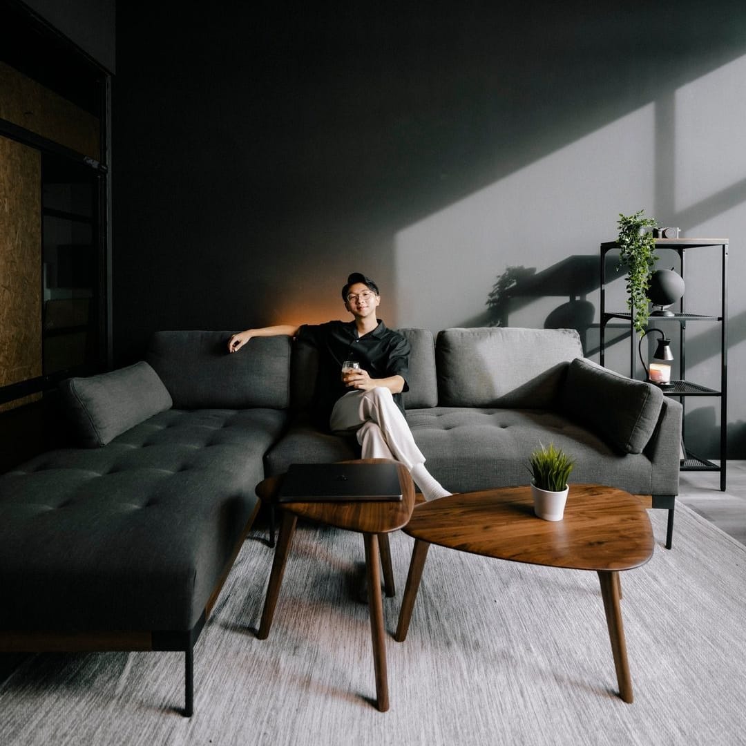 A person sitting on a dark gray sofa in a living room.