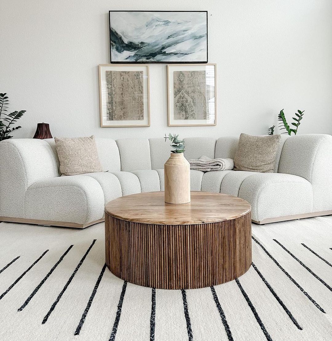 A curved bouclé sofa, a round coffee table, and a striped rug.