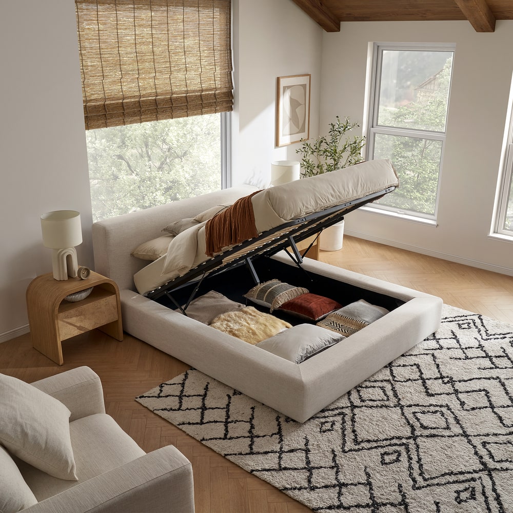 A lift-up storage bed opened to reveal bedding and cushions beneath.