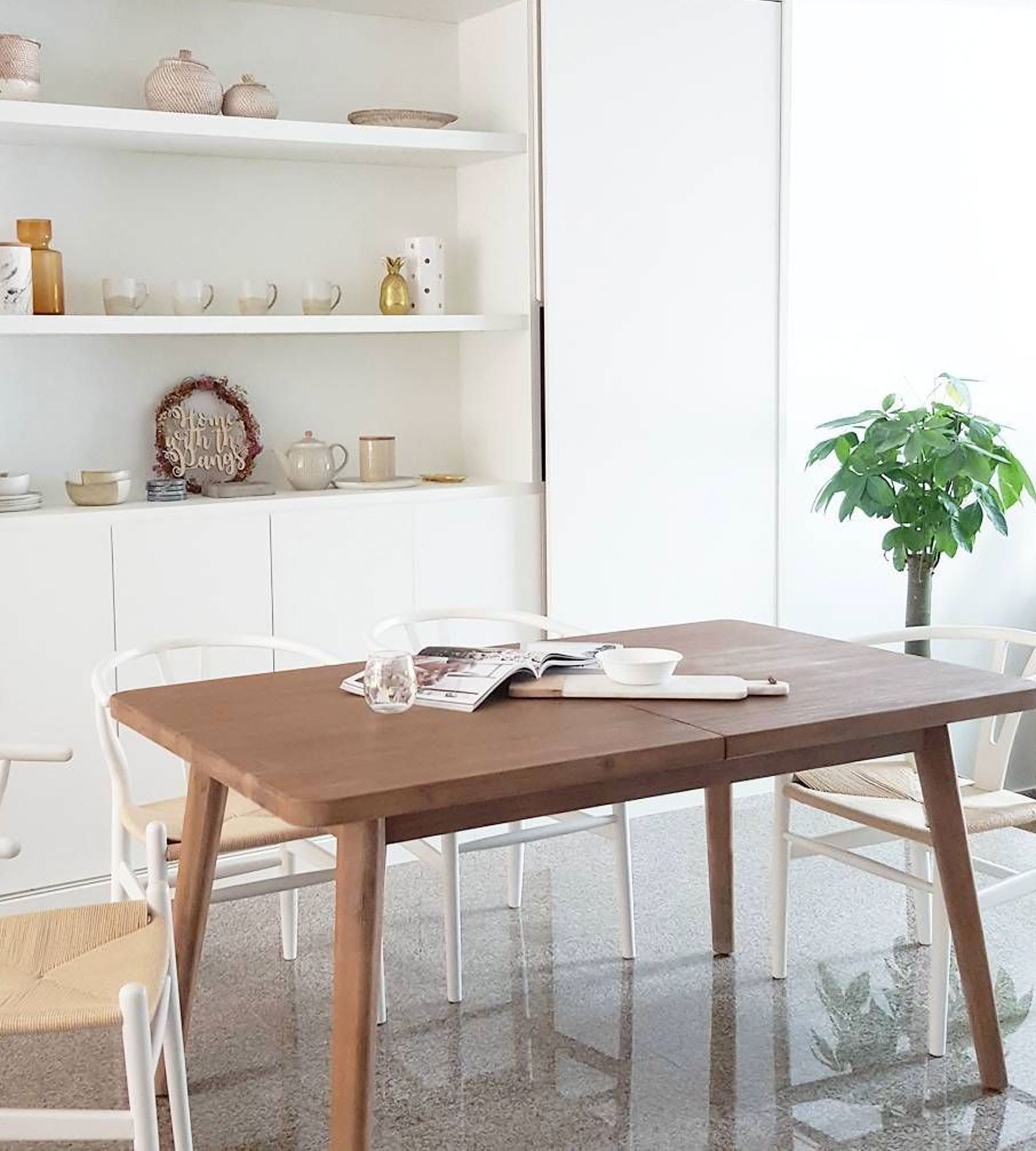 solid wood dining table in modern dining space with chairs and shelf