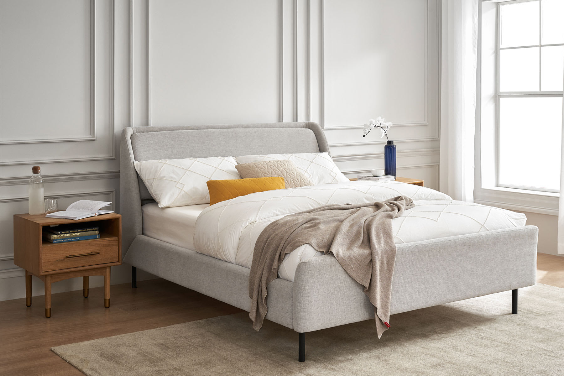 A gray bedframe with a wooden bedside table.