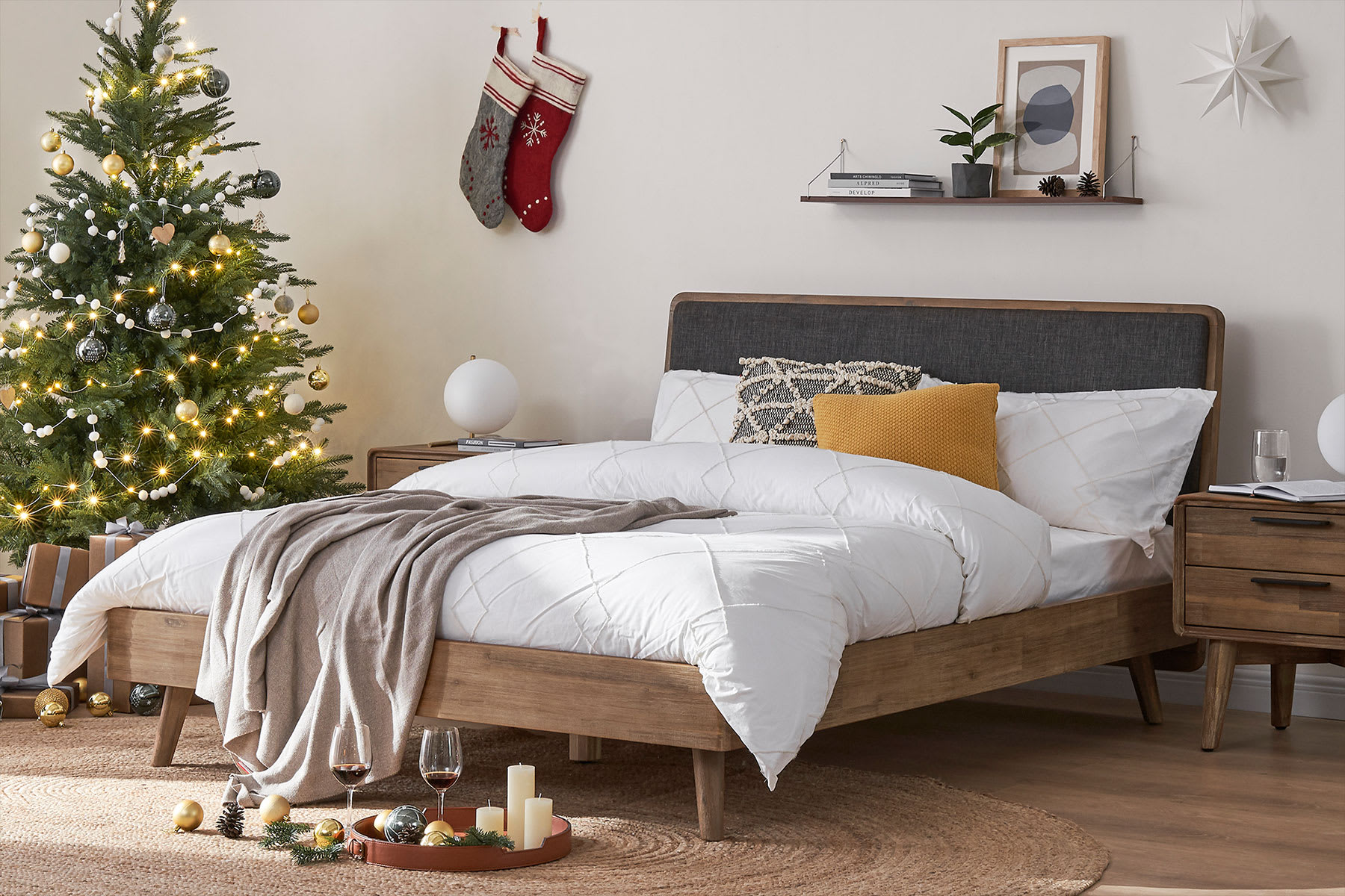 An acacia wood bed with a Christmas tree beside it.