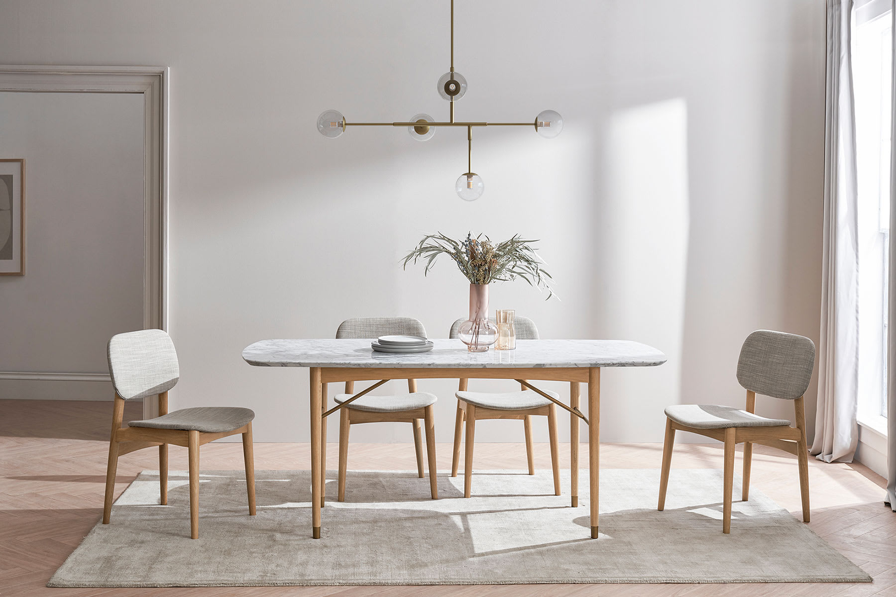 Rounded marble tapletop dining table, chairs and plant in dining room