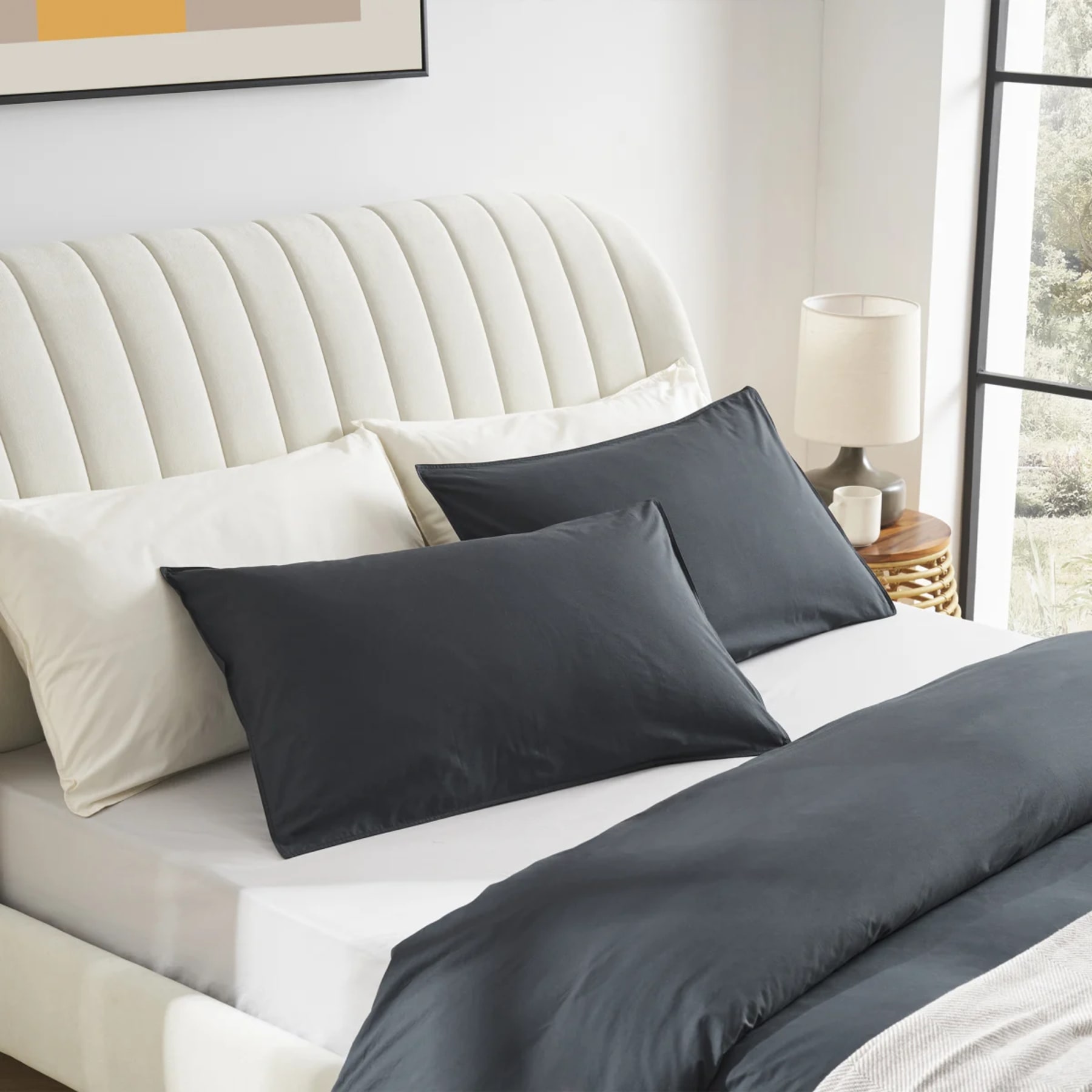 Cosy bed styled with dark duvet and neutral coloured sheets