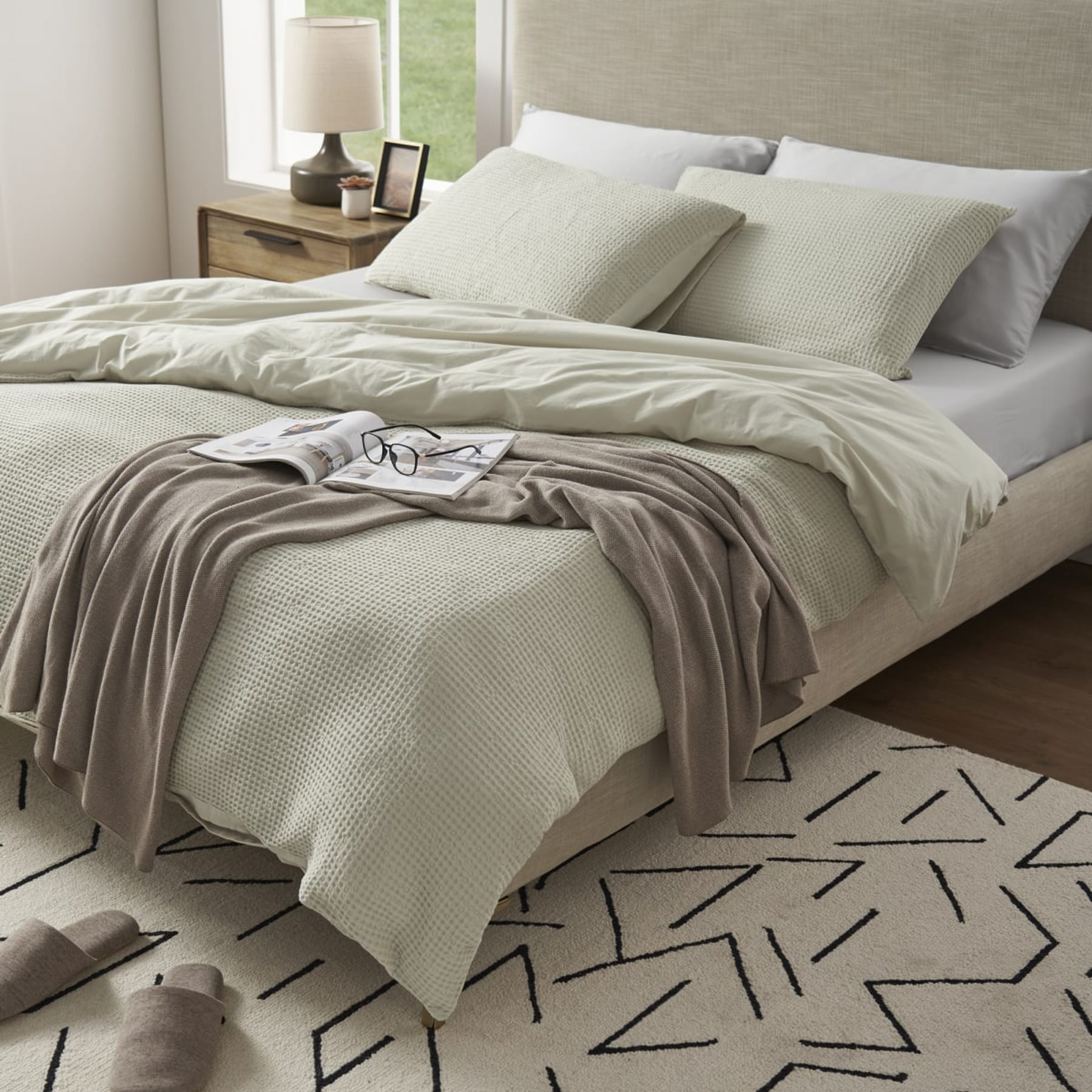 Textured bedsheets styled with muted colours in a cosy bedroom