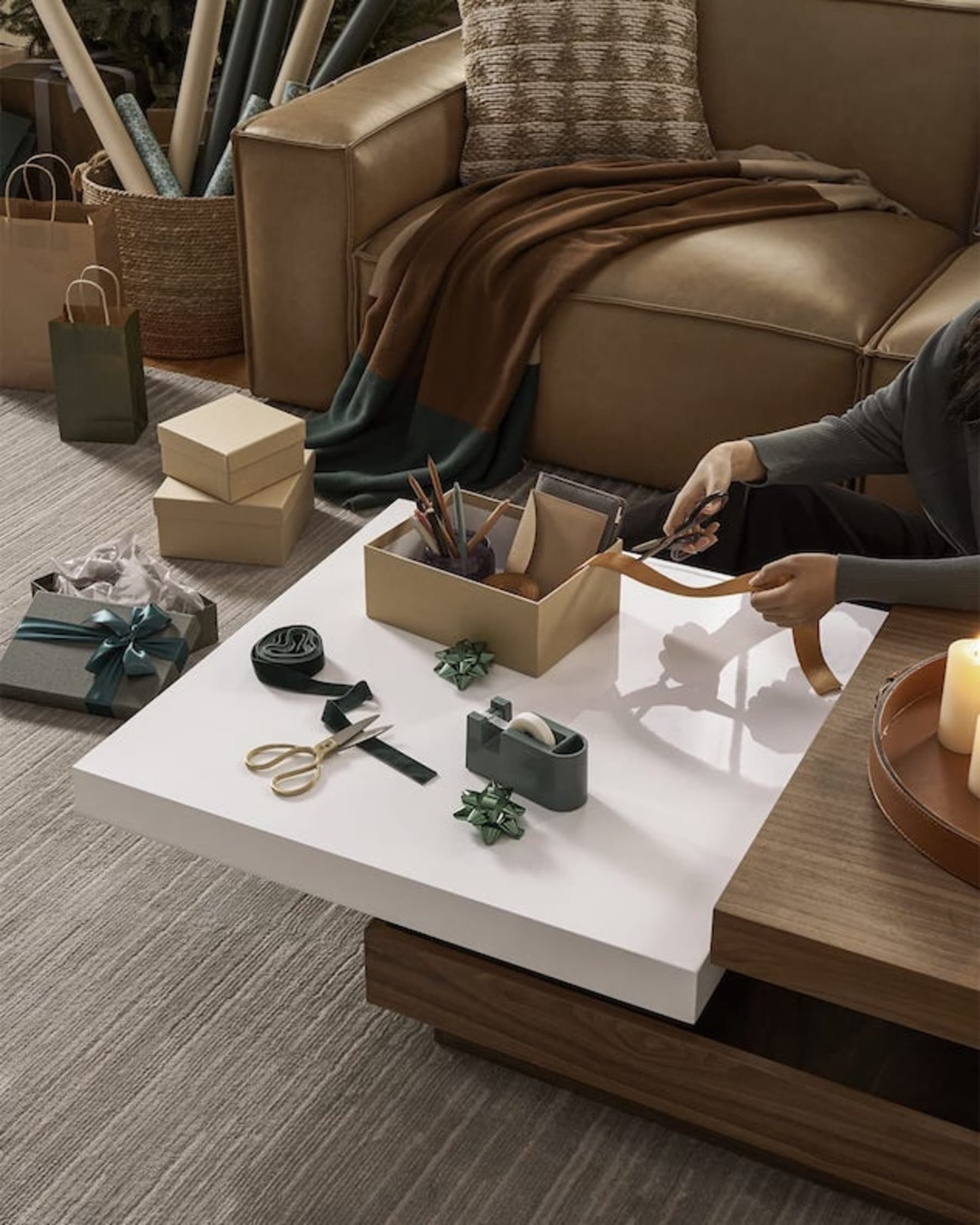 A person cutting a piece of ribbon on a coffee table.