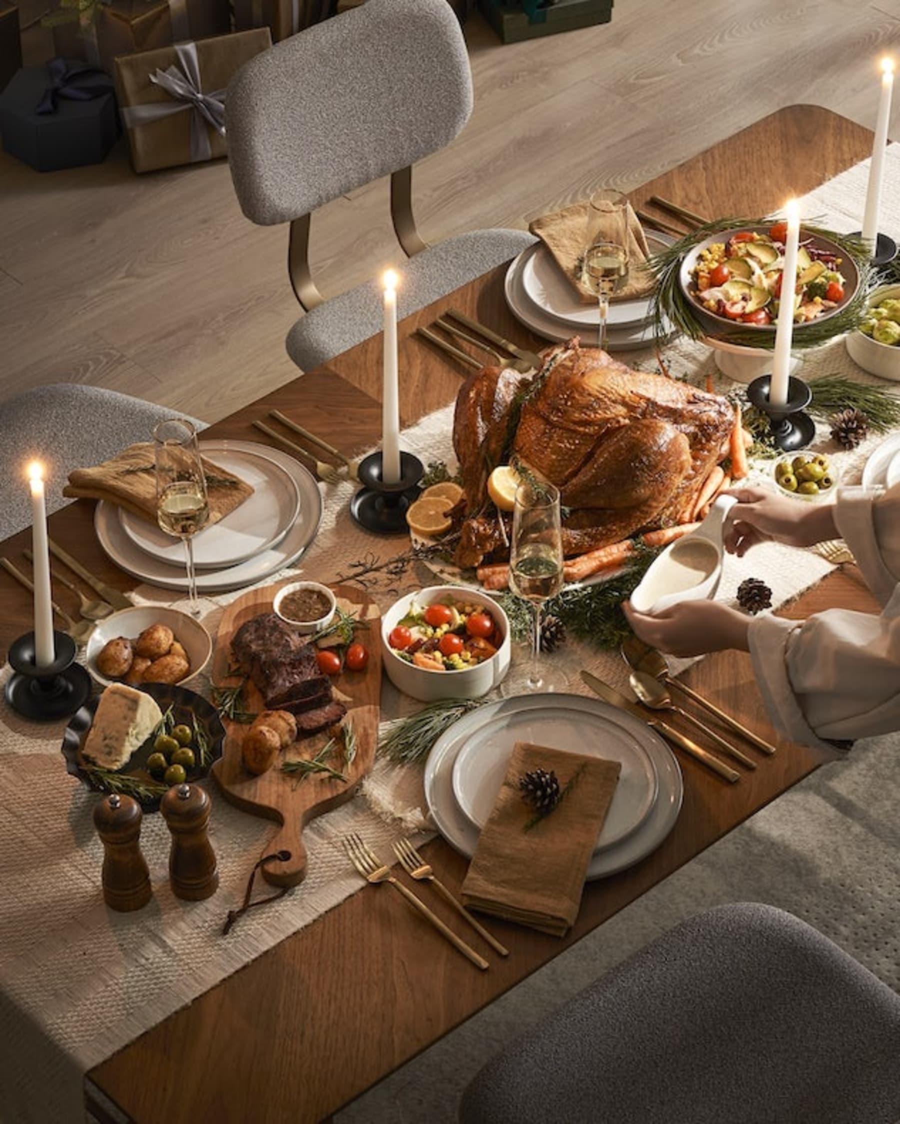 A Christmas feast with turkey, cheese, and candles on a dining table.