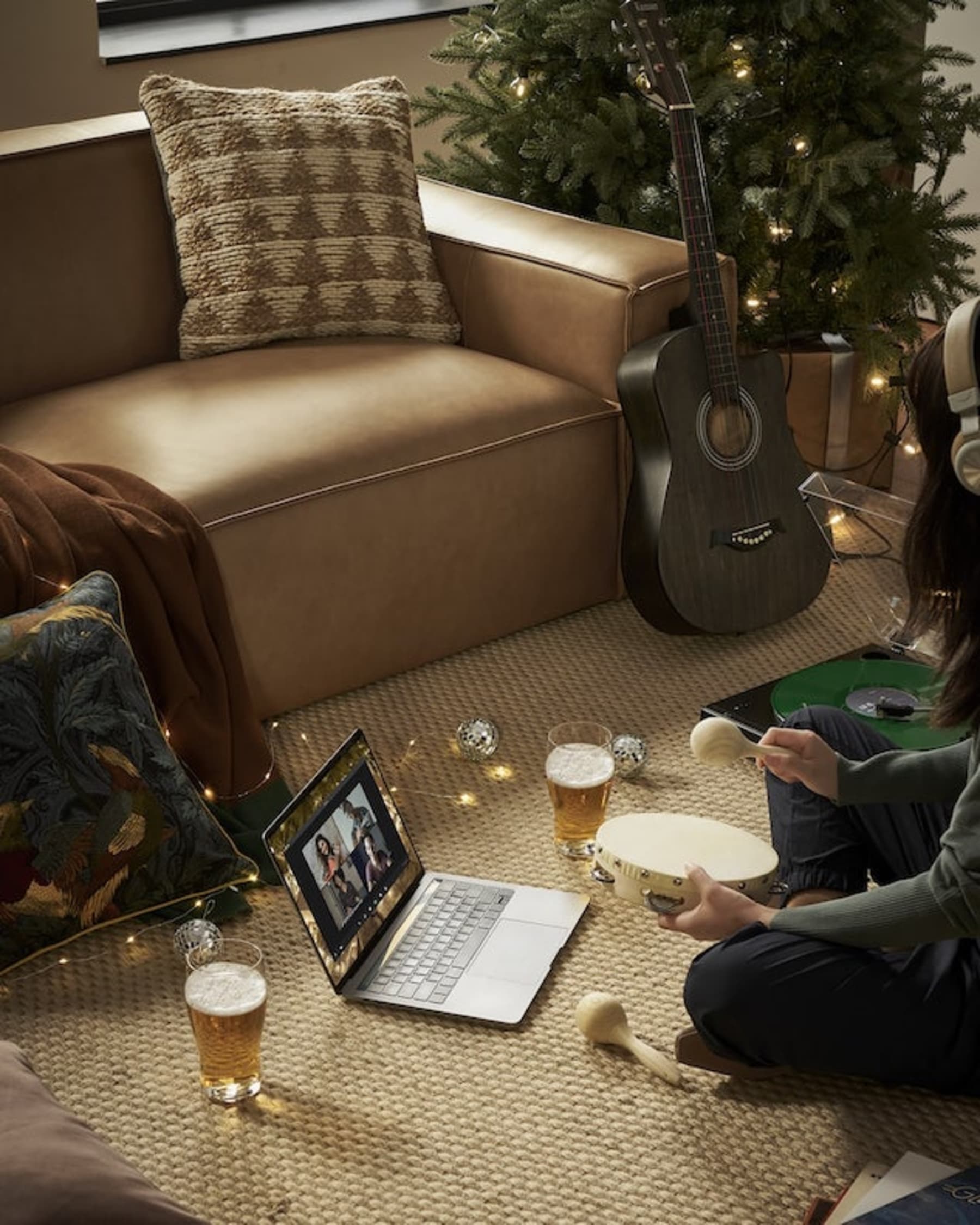 A person attending a Zoom call on a laptop while seated on the ground.