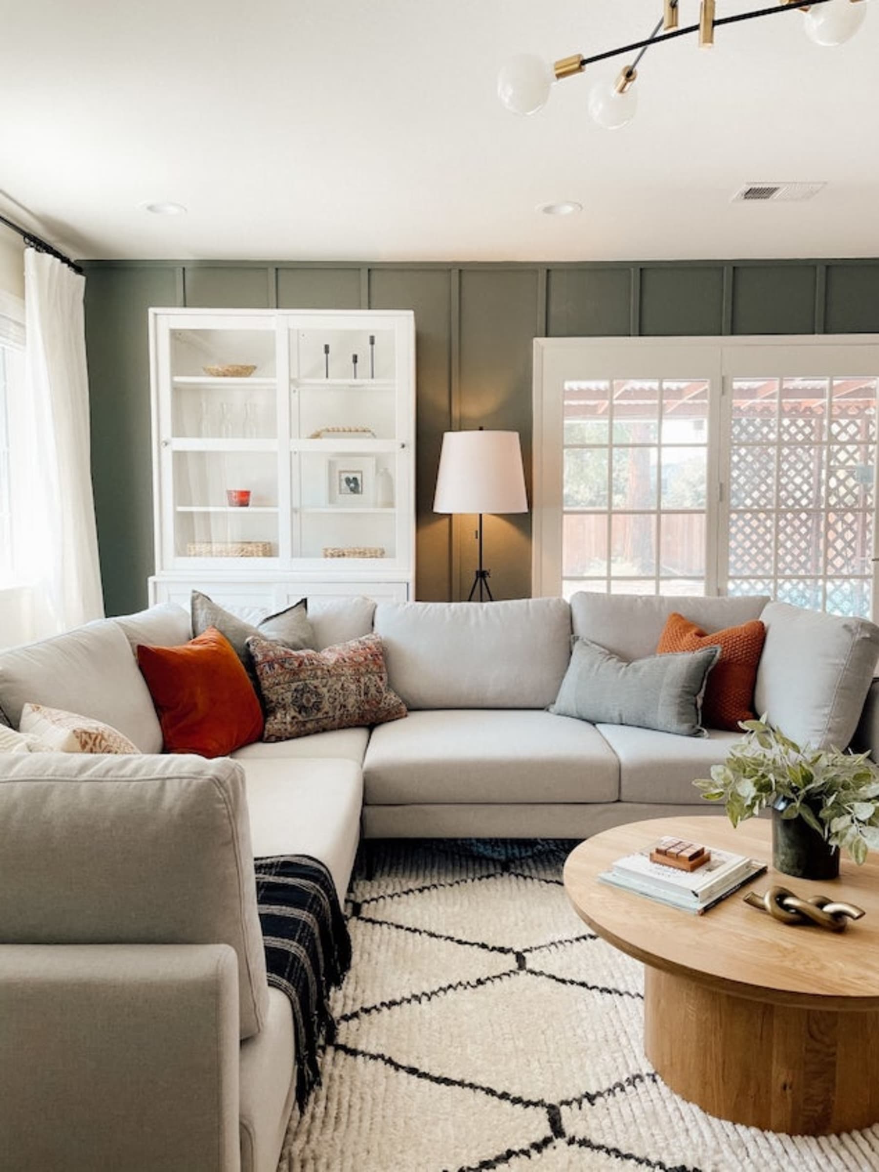 A large gray L-shaped sofa with various cushions, next to a round wooden coffee table.