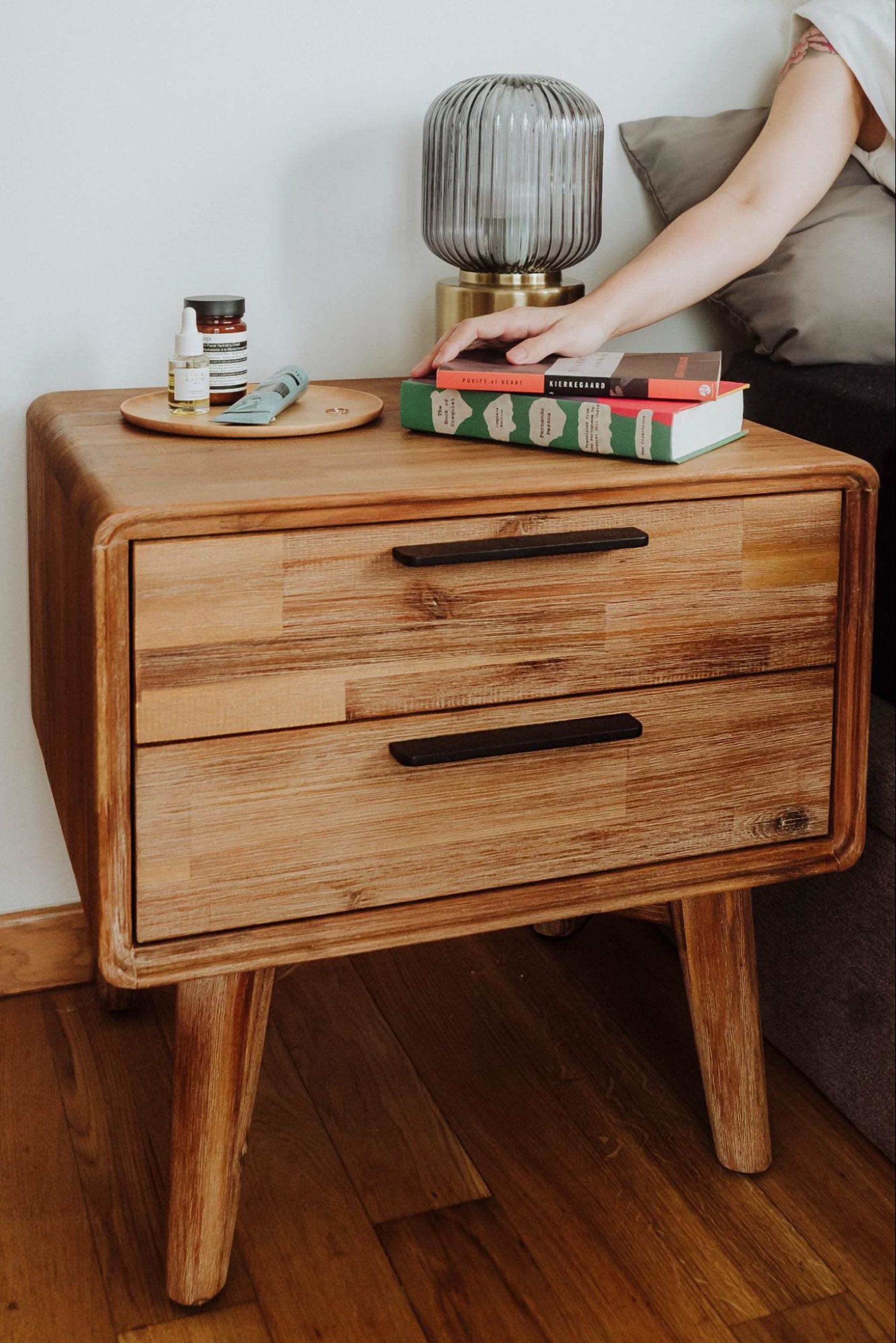 Woman’s hand reaching for a book perched on her bedside table