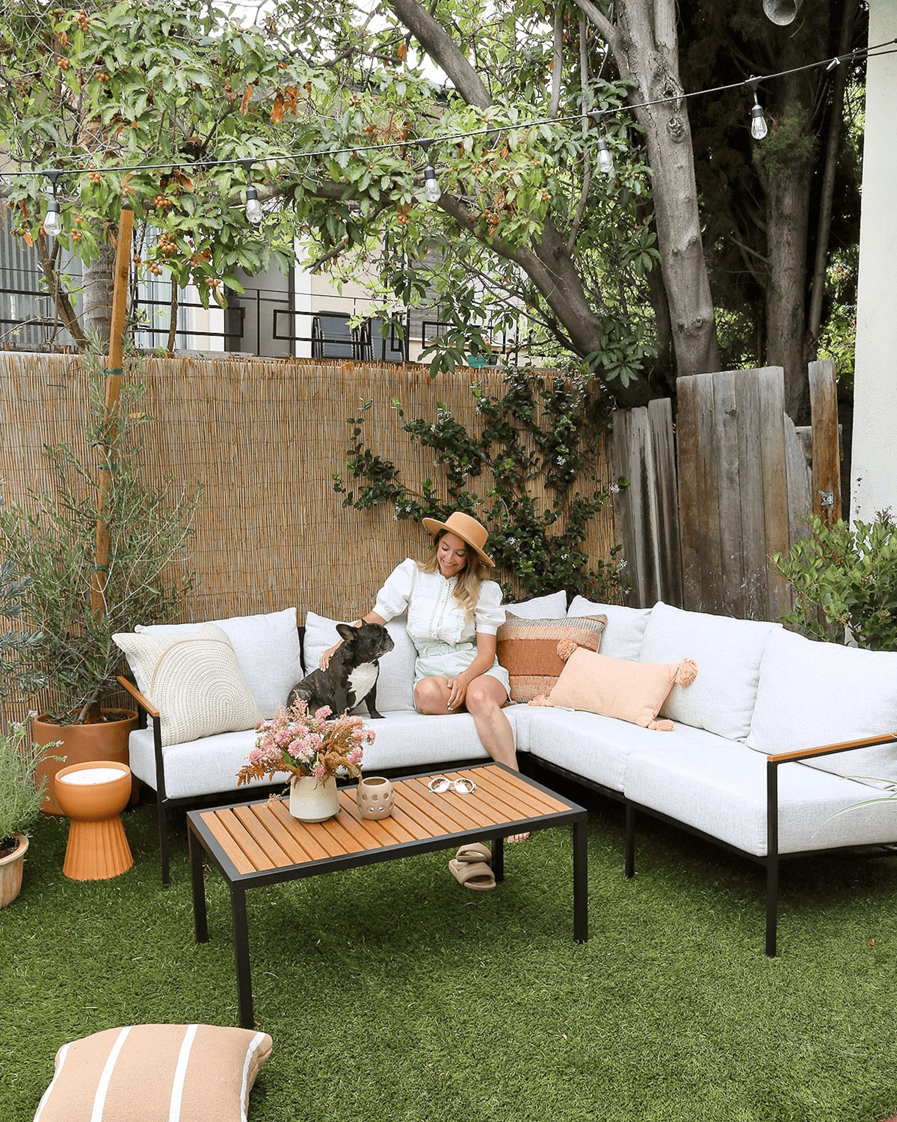 Woman and her pet dog lounging on an outdoor sofa in her backyard