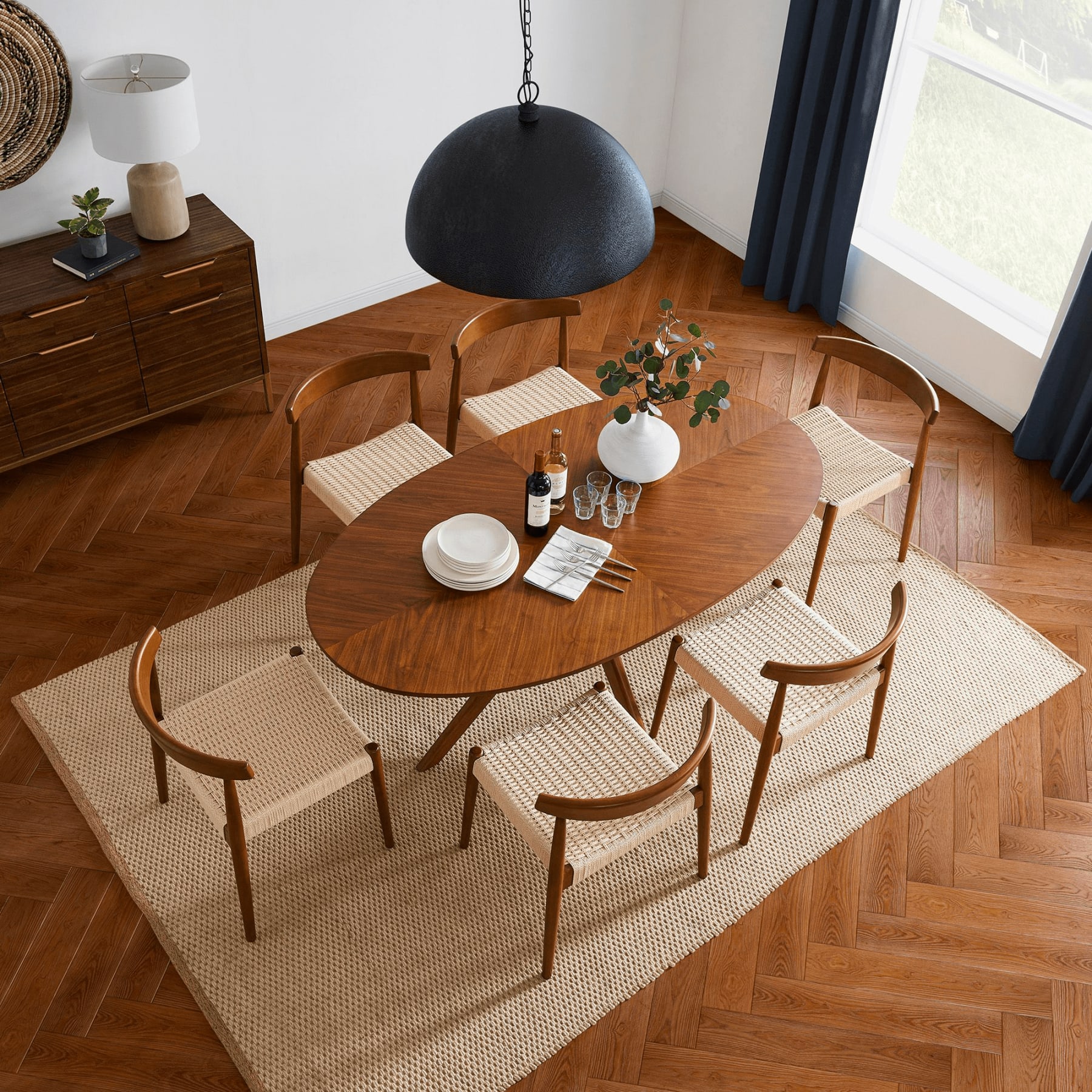 Oval mid-century modern dining table styled on a rectangular rug