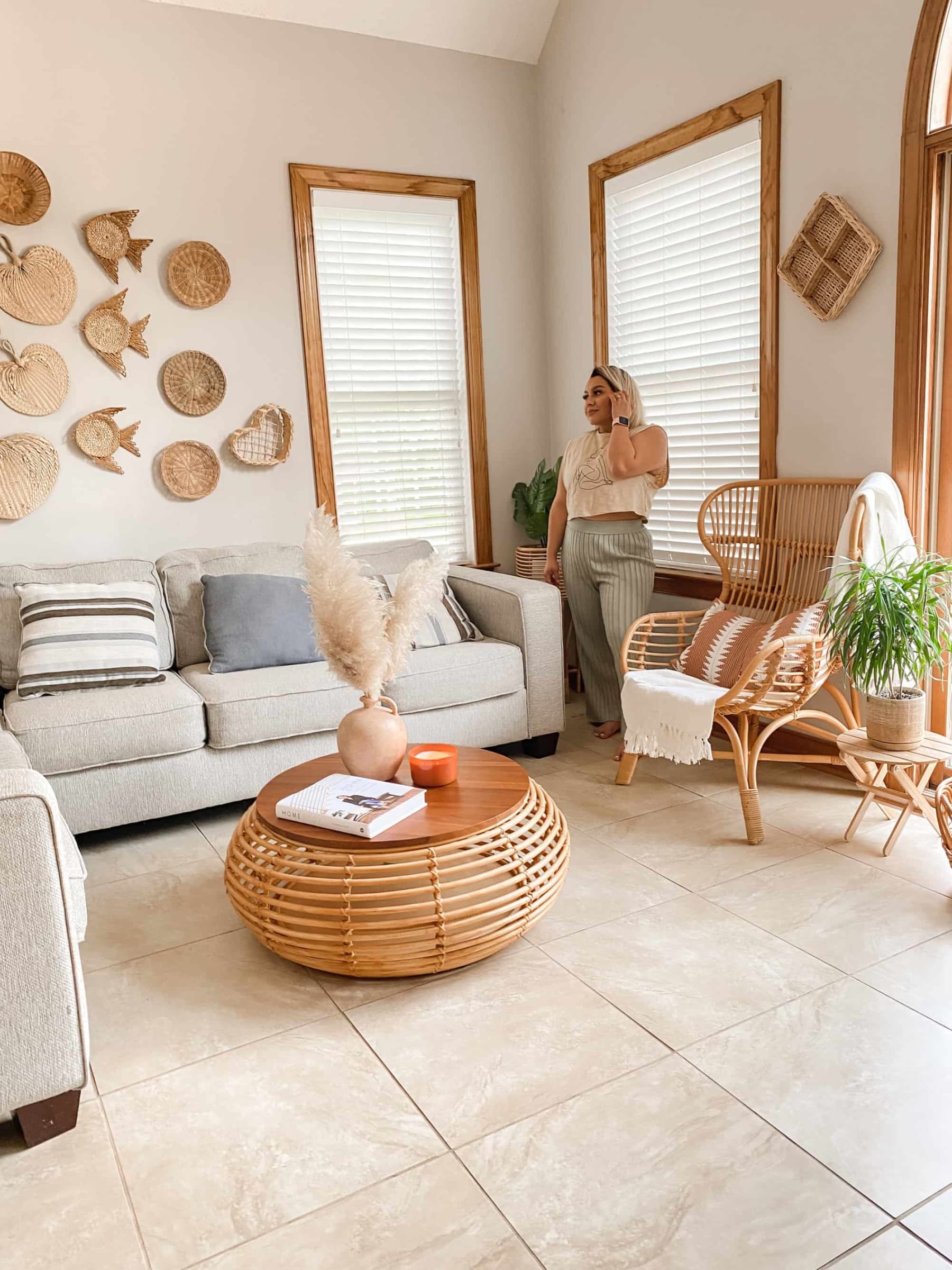 A person standing beside a sectional sofa and a rattan armchair.