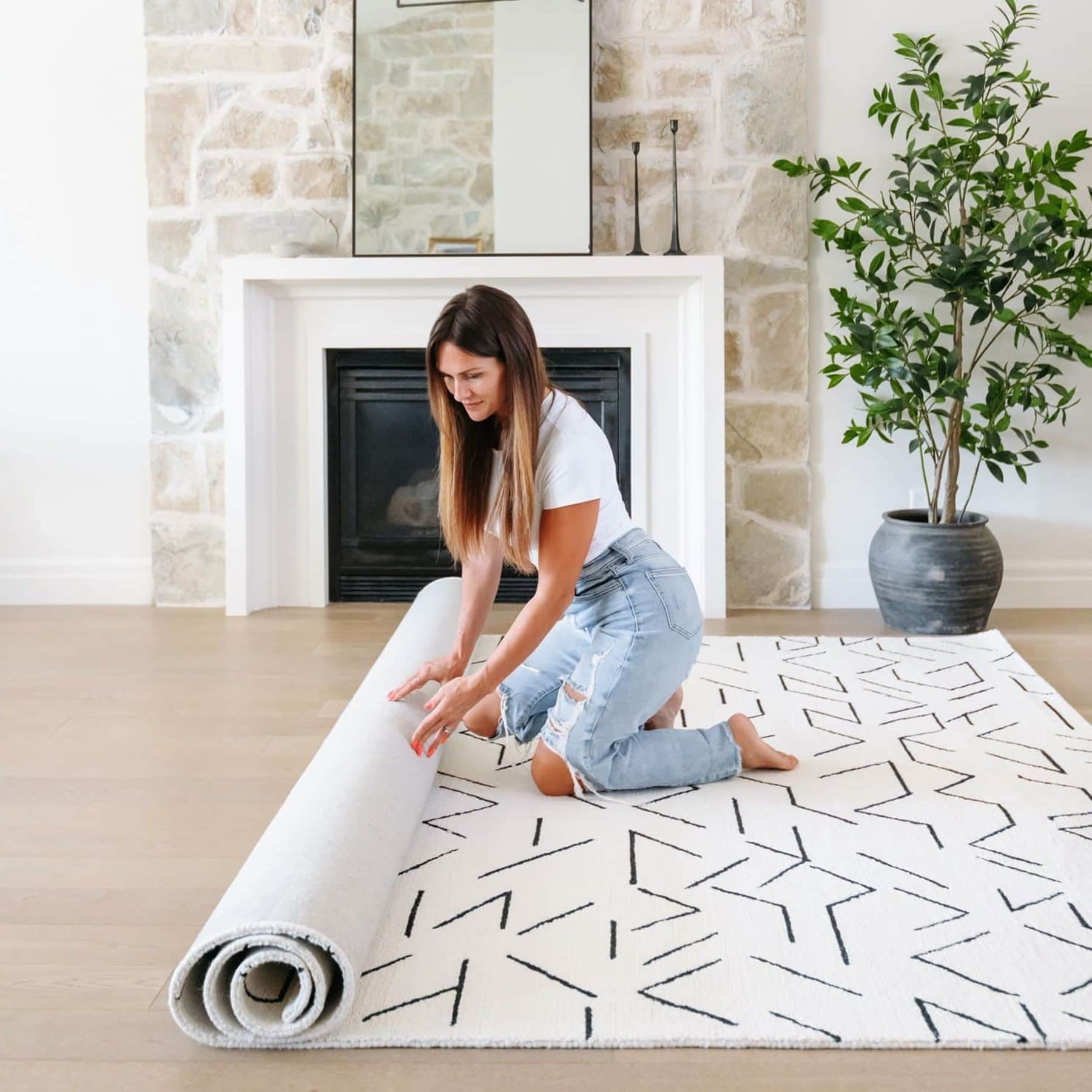 woman unrolling a patterned wool rug by the fireplace